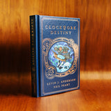 Photograph of a physical hardcover copy of Clockwork Destiny by Kevin J. Anderson and Neil Peart. The spine and front cover are and the light shines off of the faux leather texture and copper foil stamping.